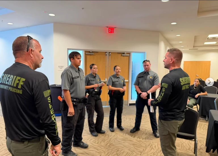 Law enforcement officers standing in a circle during a training session in an indoor meeting room